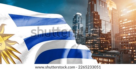 Uruguay national flag cloth fabric waving on beautiful buildings background.