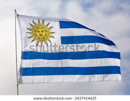 Uruguayan flag flies proudly in wind against blue sky