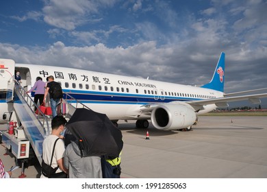 Urumqi.China-June 2021:  Travellers In Face Masks, Boarding Plane Of China Southern Airlines At Airport. A Chinese Airline Company