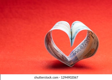 US 100 Dollar Bill In The Shape Of A Heart On A Red Background. Concept Of Money, Love And A Gift For Valentine's Day. Copy Space.