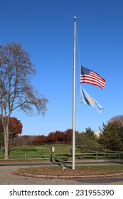 US American And Bergen County, NJ Flags At Half Mast Waving In The Wind With The Beautiful Blue Sky In Background.