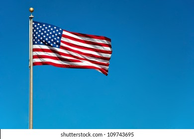 US American flag waving in the wind with beautiful blue sky in background