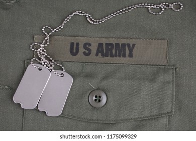 U.S. Army Branch Tape With Dog Tags On Olive Green Uniform Background