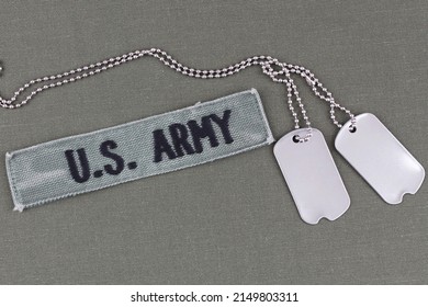 U.S. Army Branch Tape With Dog Tags On Olive Drab Uniform Background