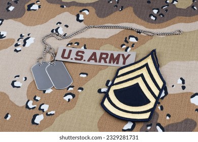 US ARMY Sergeant First Class rank patch and dog tags on desert camouflage uniform background