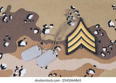 US ARMY Sergeant rank patch and dog tags on desert camouflage uniform background