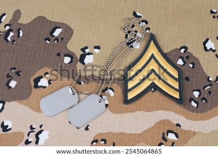 US ARMY Sergeant rank patch and dog tags on desert camouflage uniform background