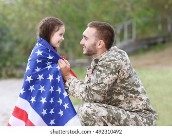 US Army Soldier With Daughter And USA Flag In Park