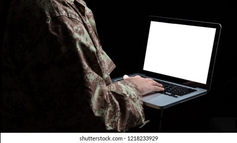 US Army. Young Soldier Working With A Laptop Computer With Blank Screen On Black Background