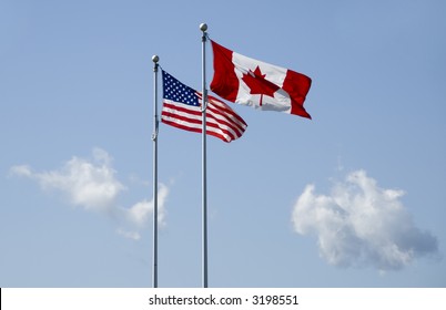 Us And Canadian Flag Blowing In The Wind On Blue Sky