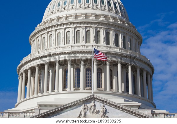 US Capitol is close\
up. American flag is on the background of the dome of the building\
of the US Congress