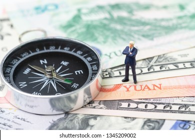 US And China Finance Economic Direction, Trade War, Import And Export Deal And Agreement Concept, Compass With Miniature Leader Standing On US Dollar And China Yuan Banknotes, Tariff Situation.