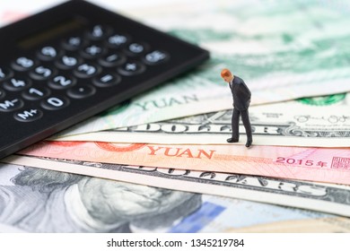 US And China Finance Economic Direction, Trade War, Import And Export Deal And Agreement Concept, Calculator With Miniature Leader Standing On US Dollar And China Yuan Banknotes, Tariff Situation.