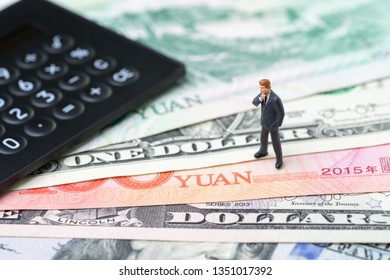 US And China Finance Economic Direction, Trade War, Import And Export Deal And Agreement Concept, Calculator With Miniature Leader Standing On US Dollar And China Yuan Banknotes, Tariff Situation.