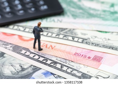 US And China Finance Economic Direction, Trade War, Import And Export Deal And Agreement Concept, Calculator With Miniature Leader Standing On US Dollar And China Yuan Banknotes, Tariff Situation.