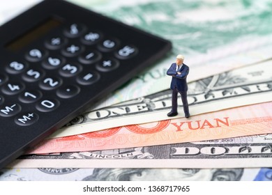 US And China Finance Economic Direction, Trade War, Import And Export Deal And Agreement Concept, Calculator With Miniature Leader Standing On US Dollar And China Yuan Banknotes, Tariff Situation.