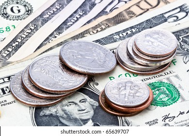 US Currency With One Dollar Coins Sitting On One Five Ten And Fifty Dollar Notes