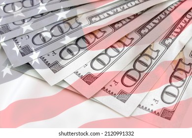 US Dollar Background With American Flag Background. Economy, Savings And The US Dollar. Several 100 US Money Notes Spread Out In Fan Shape