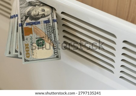 US dollar banknotes placed on home radiator symbolizing rising heating costs