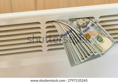 US dollar banknotes placed on home radiator symbolizing rising heating costs