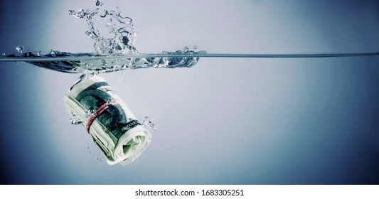 US Dollar bills sinking in water as symbol of global financiall crisis and uncertain future of international trade and investment. Horizontal image.