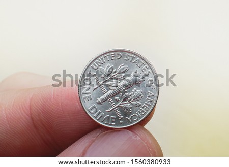 Us Dollar, Us Coins, American Cents, American Dimes. Photograph of a man holding an american dollar dime.
