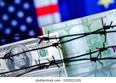 US Dollar And EU Currency Wrapped In Barbed Wire Against United States And European Union Flags As Symbol Of Joint Economic Warfare, Sanctions And Embargo Busting. Selective Focus On Dollar.