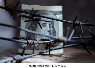 US Dollar Money Wrapped In Barbed Wire As Symbol Of Economic Warfare, Sanctions And Embargo Busting. Horizontal Image.
