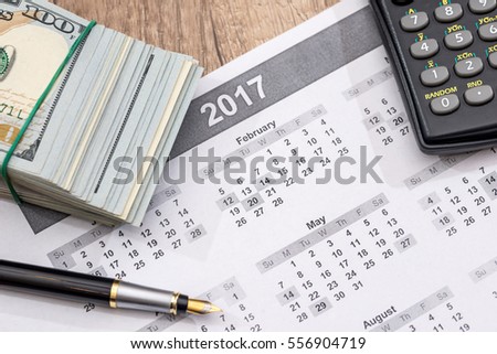 Us Dollars, calculator, pen and calendar.