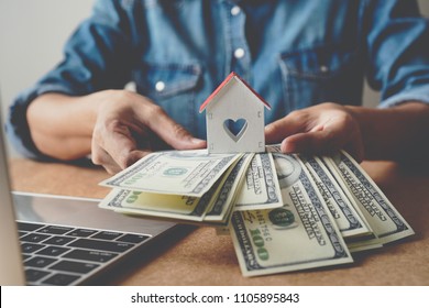 US dollars money and wooden house in hand ,Property investment and mortgage financial concept. - Shutterstock ID 1105895843