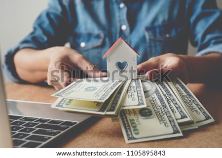 US dollars money and wooden house in hand ,Property investment and mortgage financial concept.