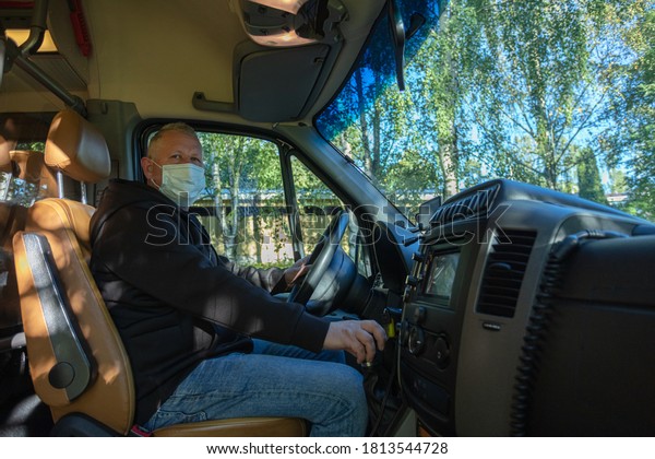 us driver in\
medical mask, leads the bus\
Safe driving during a pandemic,\
protection against\
coronavius