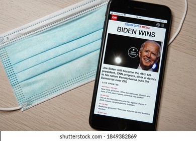 US Election 2020: US President Joe Biden Wins Over Donald Trump. Live Preview Of Election Results On Your Mobile Phone Screen. Medical Mask And Phone On A Wooden Table.