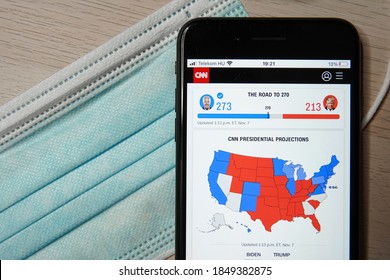 US Election 2020: US President Joe Biden Wins Over Donald Trump. Live Preview Of Election Results On Your Mobile Phone Screen. Medical Mask And Phone On A Wooden Table.