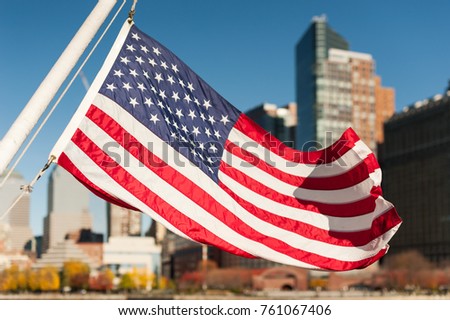 US flag floating with New-York city buildings in the background, USA