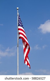 US Flag  waving on Pole against a blue, cloud-draped sky. Vertical.