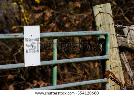 US Government Property sign on locked gate with thick woods in background close crop. Illustrates government land, control, eminent domain laws and land grabs