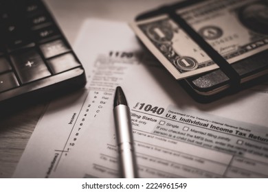 U.S. Individual And Corporation Income Tax Return Close-up Next To A Calculator, Dollars, Money, A Pen And A Notepad On A Wooden Table. Retro Old Style Photo.