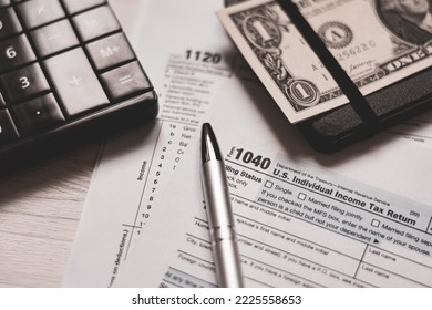 U.S. Individual And Corporation Income Tax Return Close-up Next To A Calculator, Dollars, Money, A Pen And A Notepad On A Wooden Table. Retro Old Style Photo.