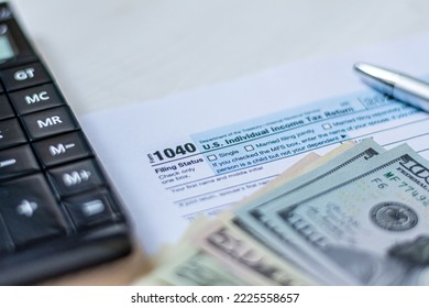 U.S. Individual Income Tax Return On A Wooden Table Next To A Calculator, Dollars, Money, A Pen And A Notepad. Blank US Tax Forms.