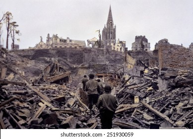 U.S. infantry patrol picking its way through the blasted ruins of Saint Lo. The town was 95% destroyed before it was captured from Germans on July 18, 1944. B&W Photo with oil color.