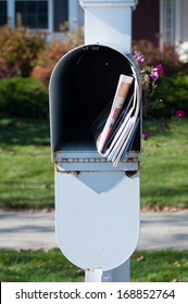 US Mail Box With Newspaper And Letters In Front Of A House