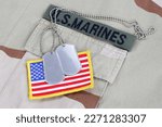 US MARINES branch tape with dog tags and flag patch on desert camouflage uniform background