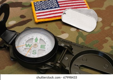 US Military Compass And US Flag Patch And Dog Tags On Multicam Camo Background