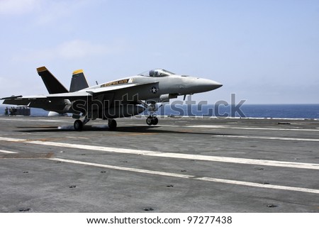 u.s navy f18 fighter jet landing on an aircraft carrier