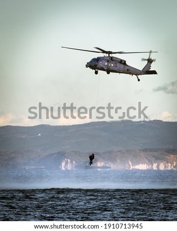 A US Navy MH-60 helicopter hovers while rescue swimmers train in Tokyo Bay.