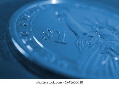 US one dollar coin close-up. Dark blue tinted background or wallpaper. American money, economy, finance or debt market. Background on an economic, business or financial topic. Macro