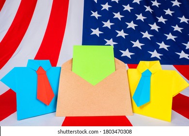 US President Election. Envelope With A Piece Of Paper For Your Text On The Background Of The Us Flag. Voting For The American Presidential Nominee. Origami Men And An Envelope Next To The USA Flag.