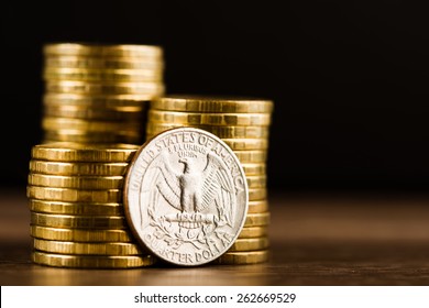 Us Quarter Dollar Coin And Gold Money On The Desk