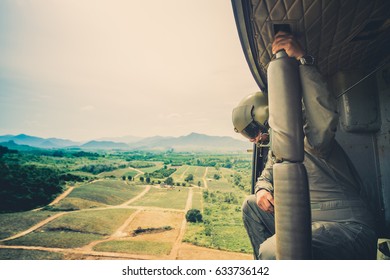 US Soldier In The Desert During The Military Operation Turning To Combat Helicopter Approaching Covering His Eyes. Backup Is Coming